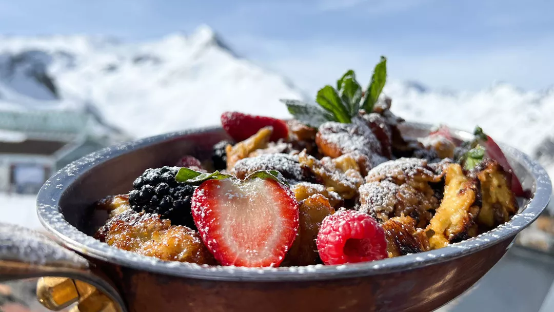 Kaiserschmarrn mit Früchten vor Bergkulisse im Skiurlaub