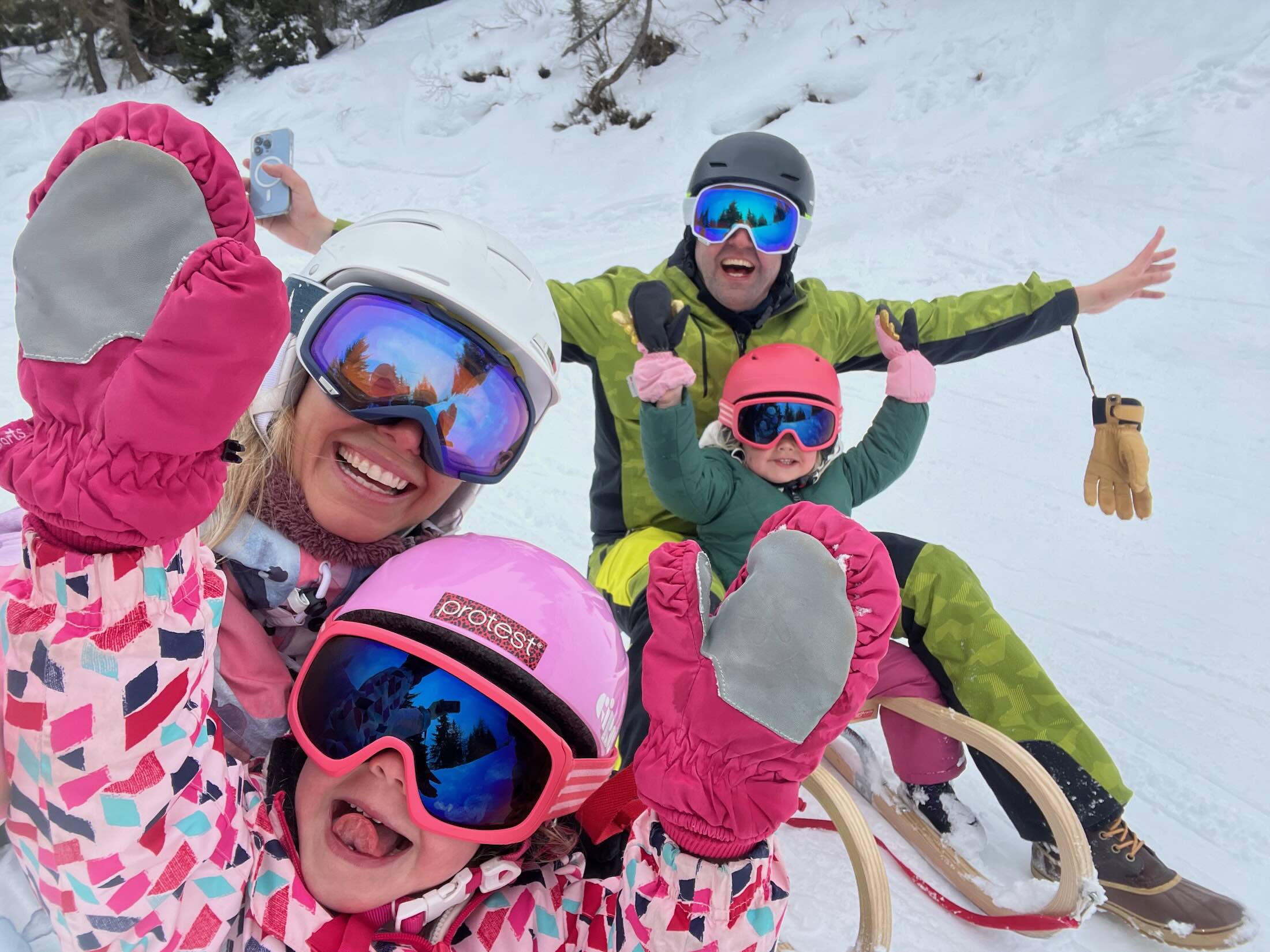 Familie macht Spaß und Grimassen beim Rodeln