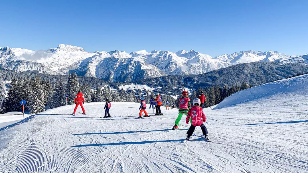 Skiklasje achter skileraar tijdens wintersport met kinderen
