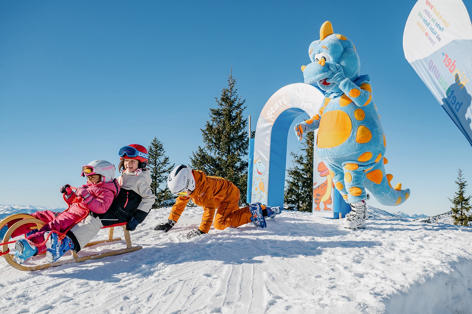 Kinder haben Spaß im Schnee mit Maskottchen im Skigebiet Steinplatte