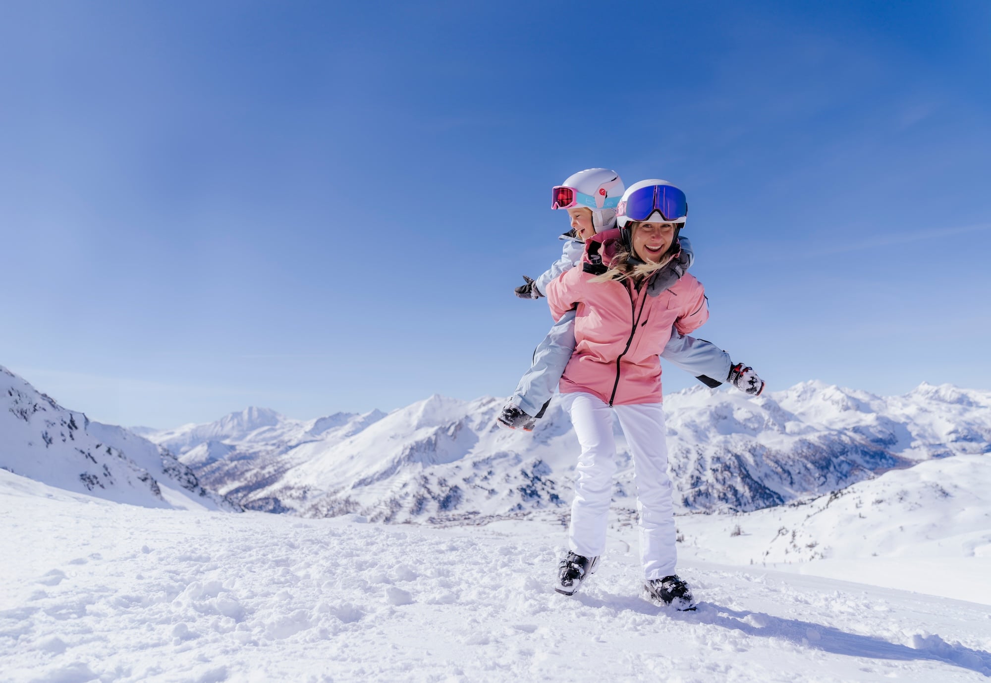 Moeder met kind op rug lachend staand in sneeuw